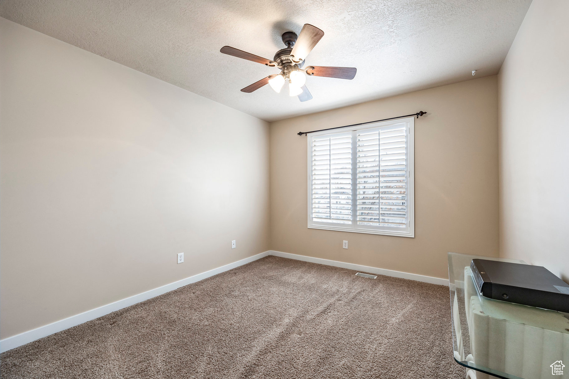 Unfurnished room featuring ceiling fan, carpet floors, and a textured ceiling