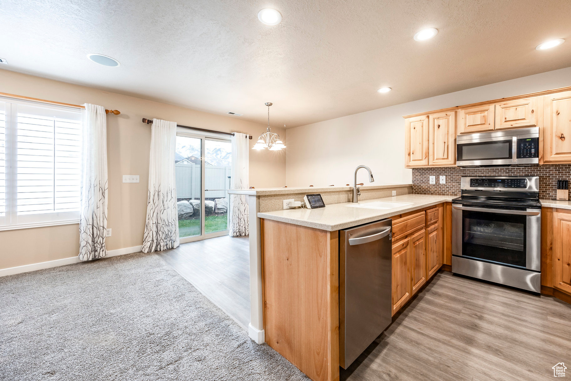 Kitchen featuring kitchen peninsula, appliances with stainless steel finishes, pendant lighting, and sink