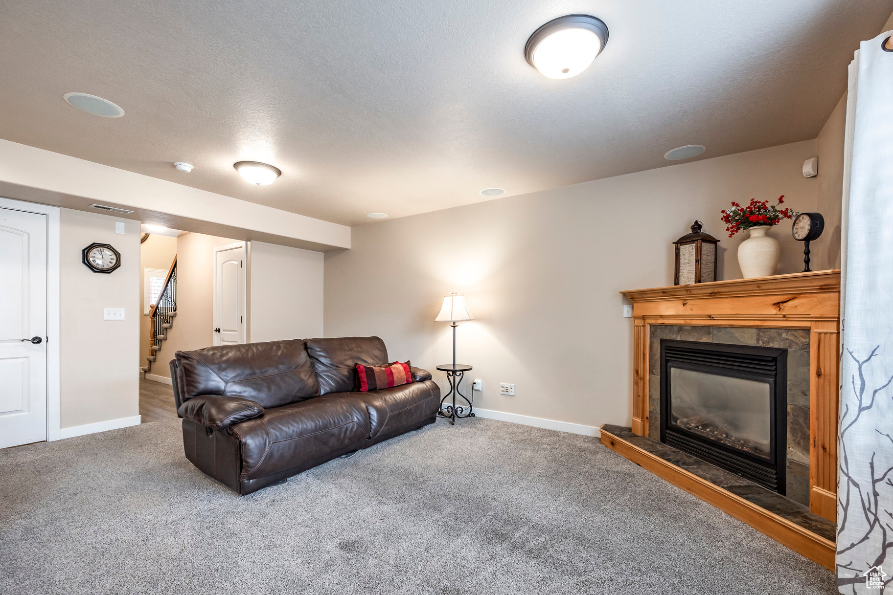 Living room featuring carpet flooring, a textured ceiling, and a tiled fireplace