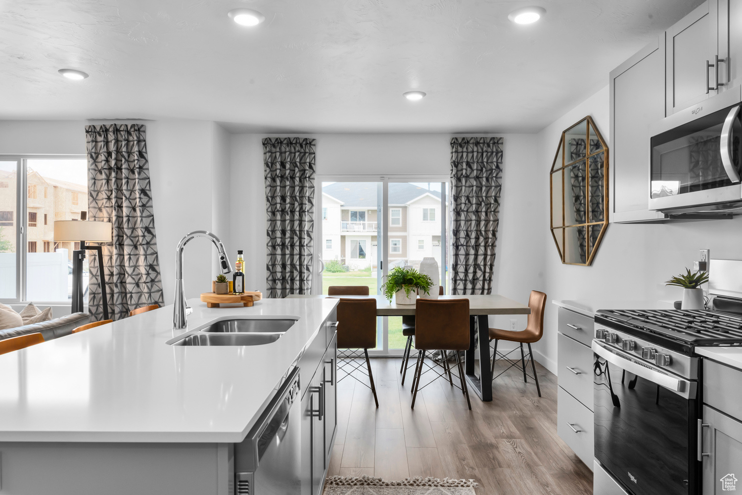 Kitchen featuring gray cabinetry, sink, light hardwood / wood-style flooring, an island with sink, and appliances with stainless steel finishes