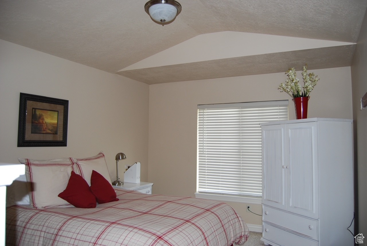 Bedroom with a textured ceiling and vaulted ceiling