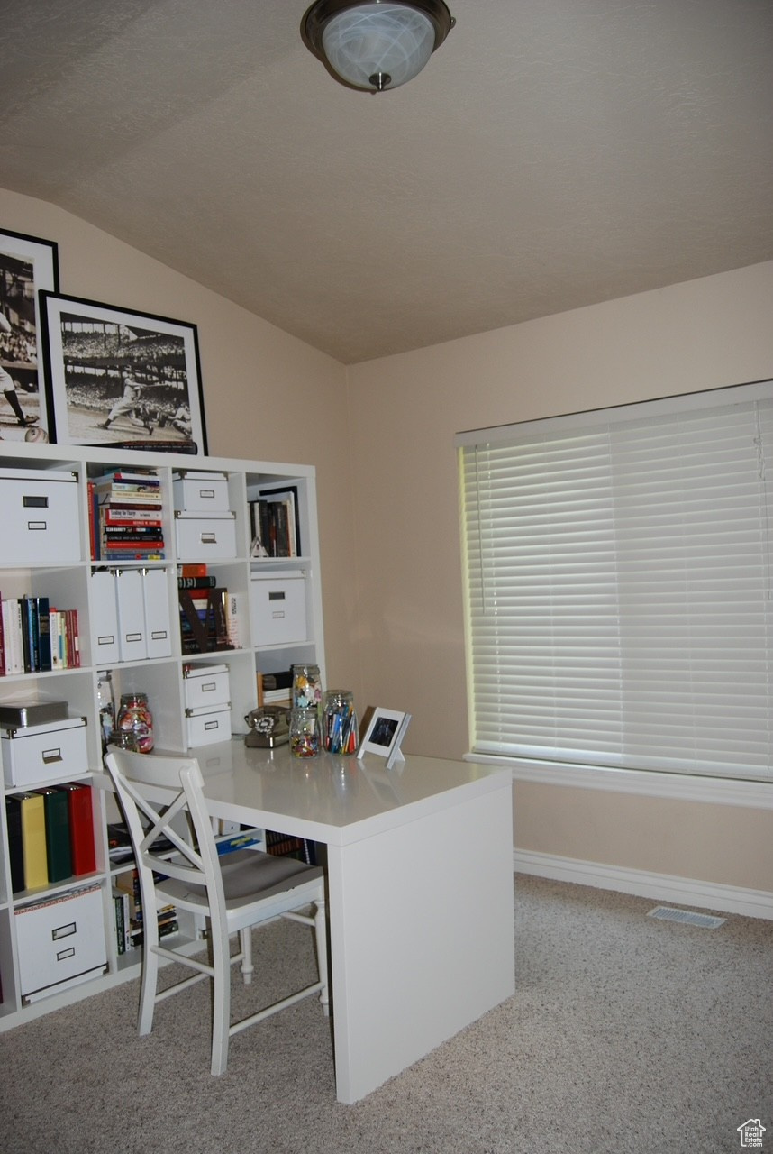 Office with light colored carpet and lofted ceiling