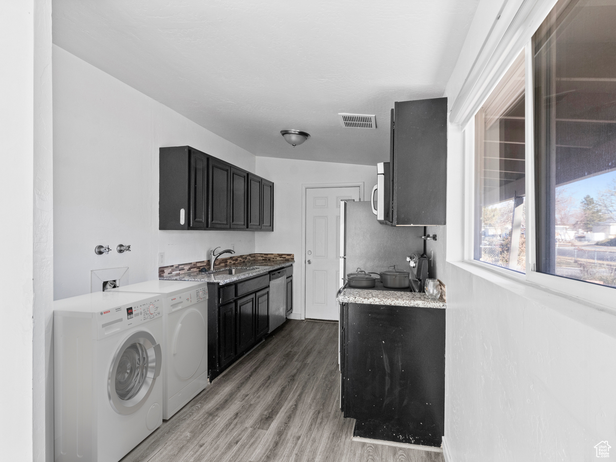 Kitchen featuring independent washer and dryer, wood-type flooring, sink, and appliances with stainless steel finishes