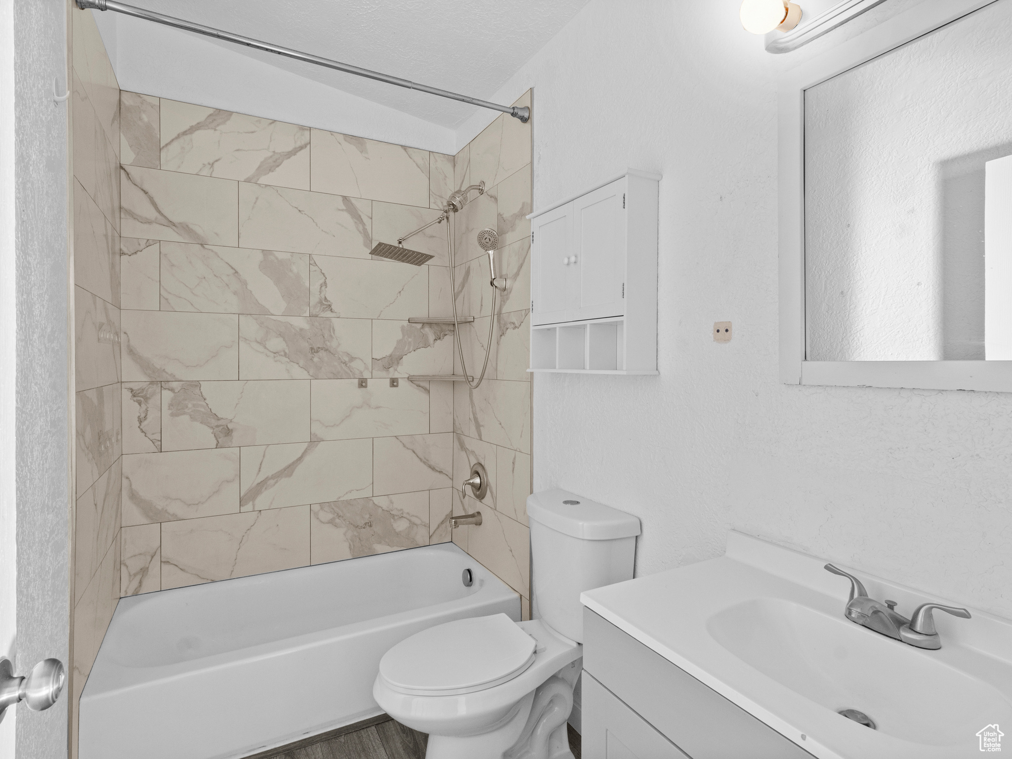 Full bathroom with vanity, tiled shower / bath combo, and toilet