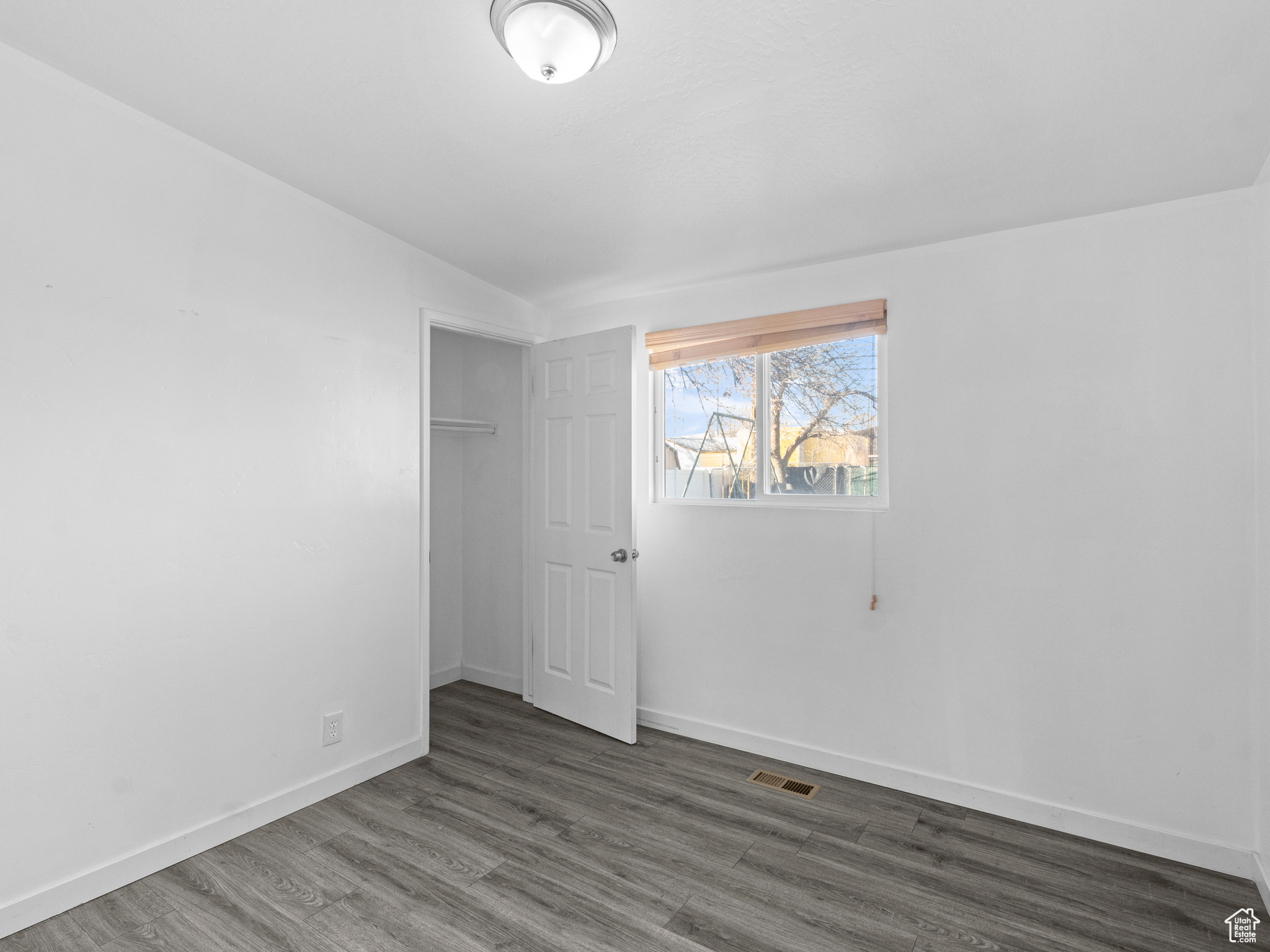 Unfurnished bedroom with lofted ceiling, a closet, and dark hardwood / wood-style floors