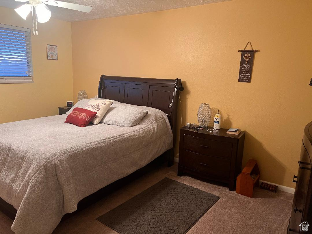 Bedroom with carpet flooring, ceiling fan, and a textured ceiling