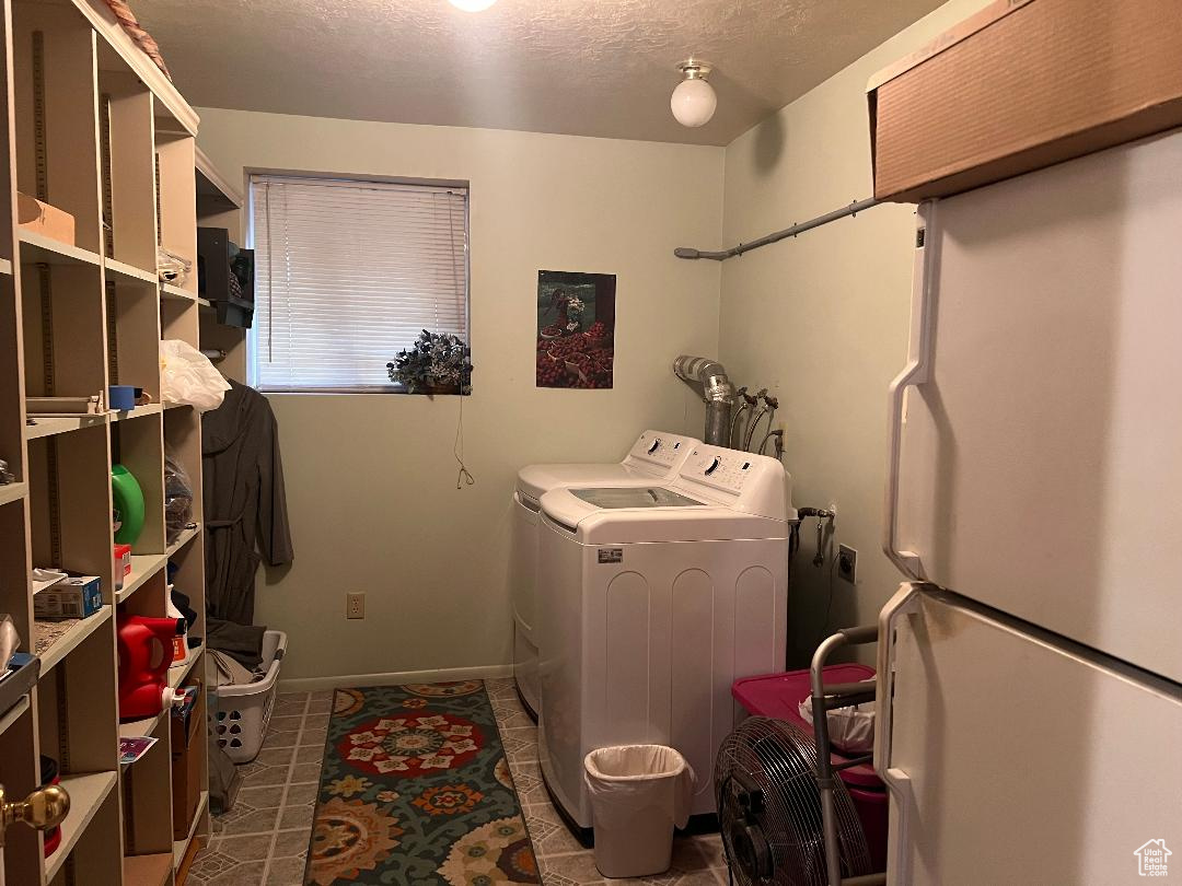 Laundry room featuring a textured ceiling, washing machine and dryer, and dark tile patterned flooring