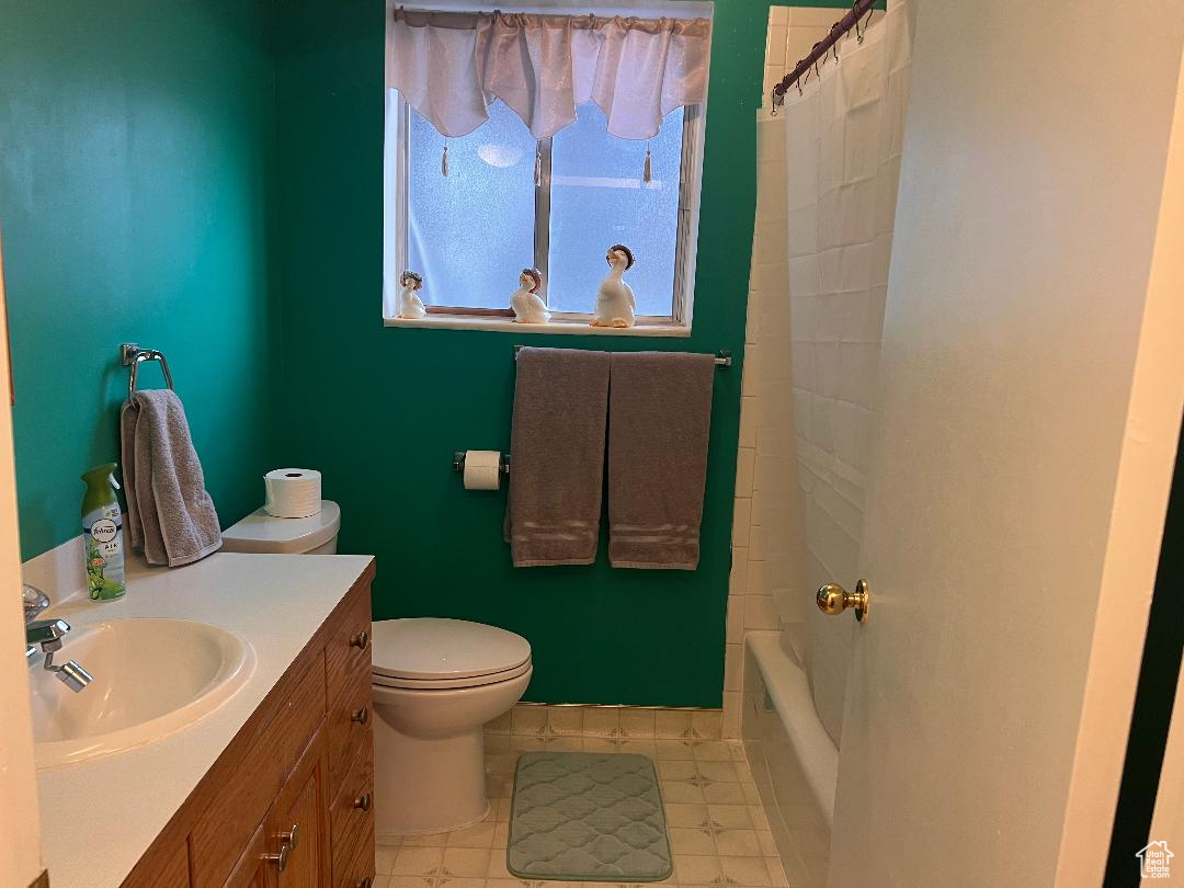 Full bathroom featuring shower / bath combination with curtain, vanity, and toilet