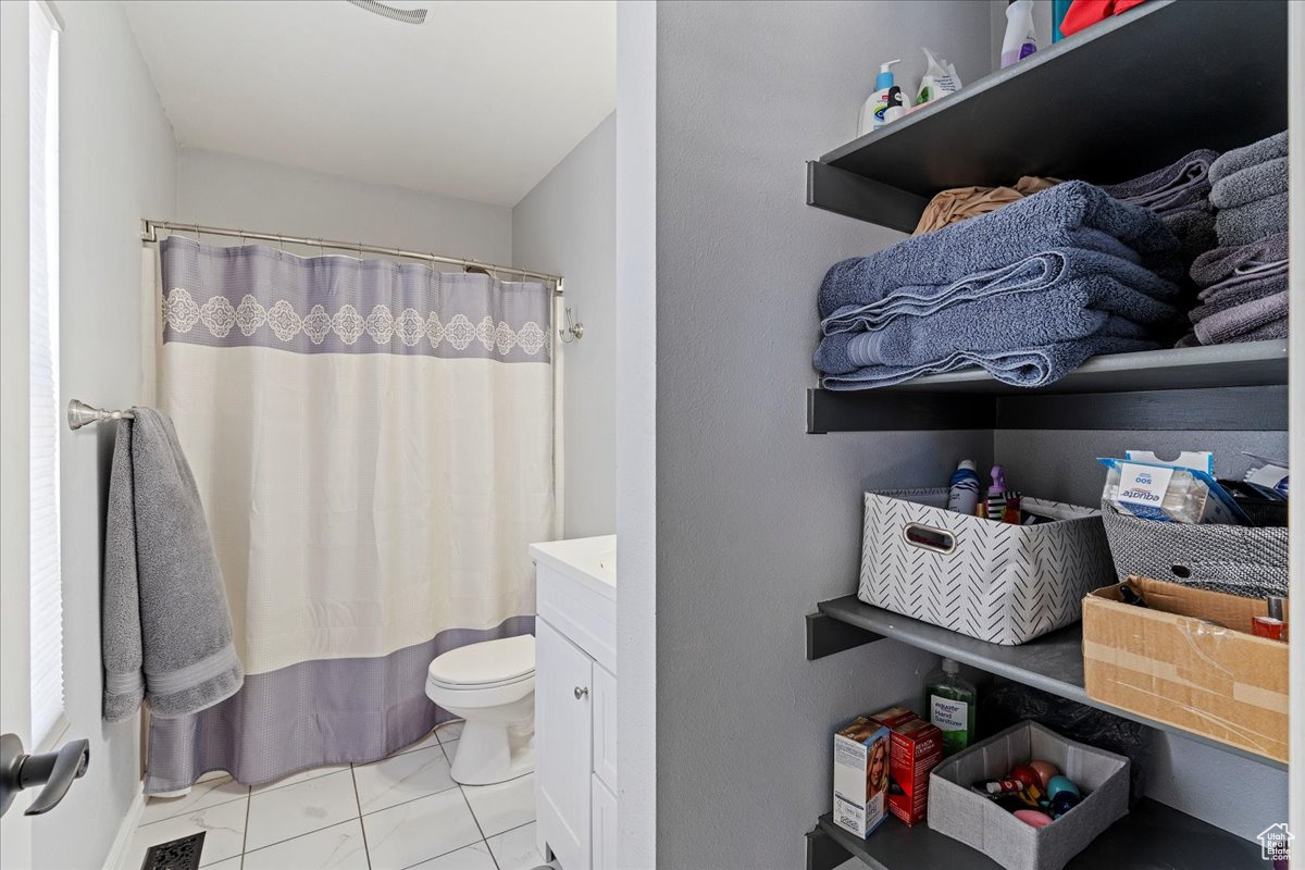 Bathroom with vanity, a shower with shower curtain, and toilet