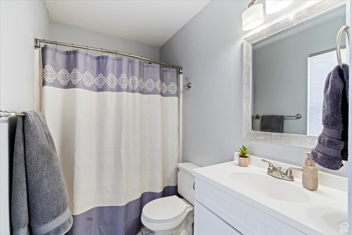 Bathroom with vanity, a shower with shower curtain, and toilet