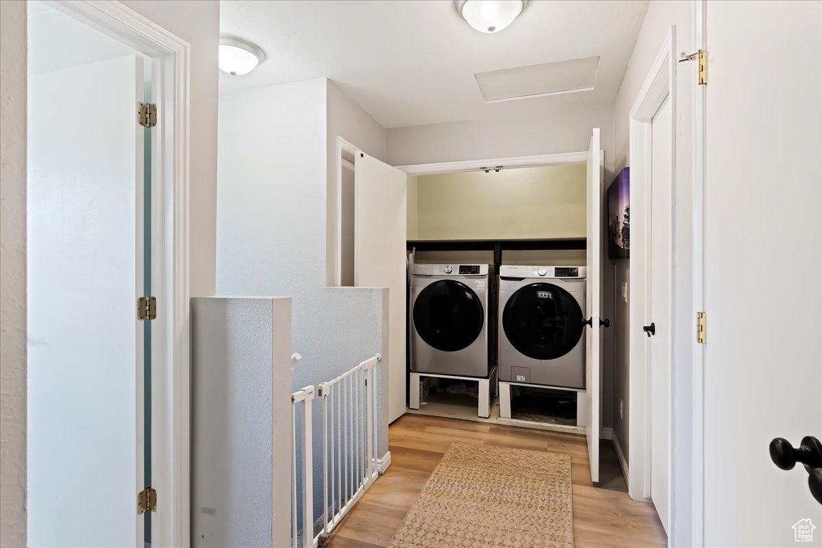 Washroom with washer and dryer and light hardwood / wood-style flooring