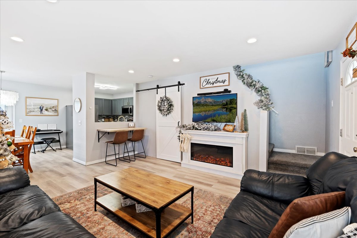 Living room with a barn door and light hardwood / wood-style floors