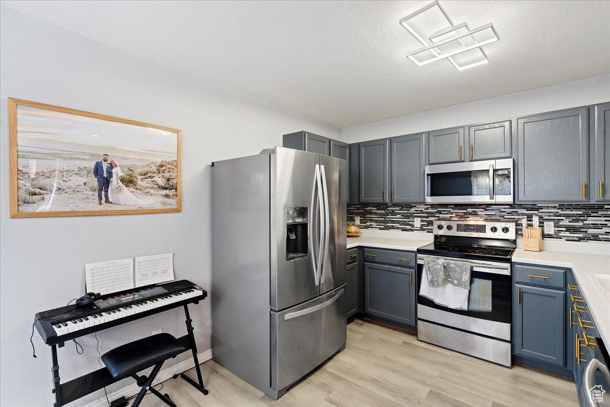 Kitchen featuring light hardwood / wood-style floors, backsplash, and appliances with stainless steel finishes