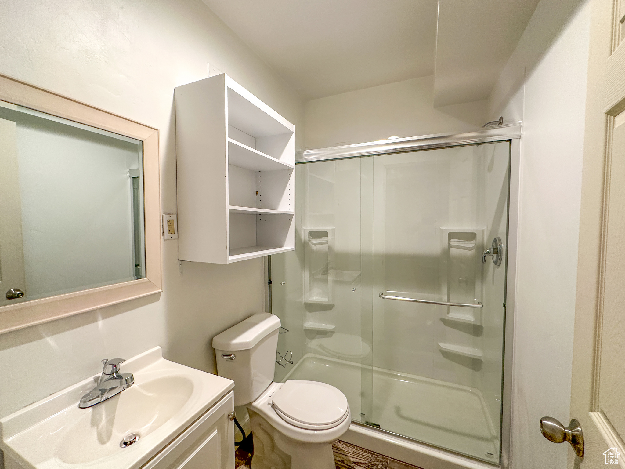 Bathroom featuring vanity, toilet, and a shower with door