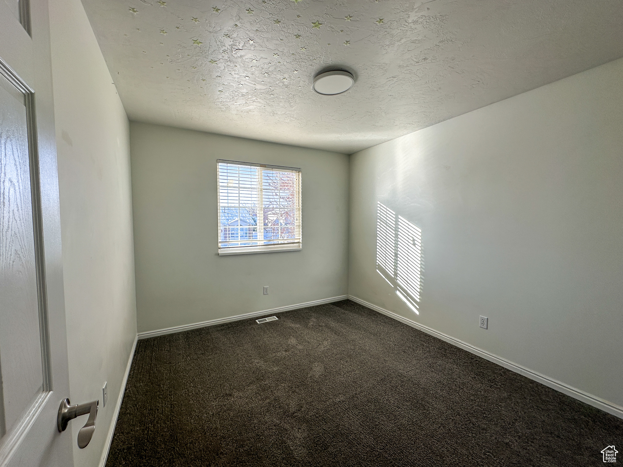 Carpeted spare room featuring a textured ceiling