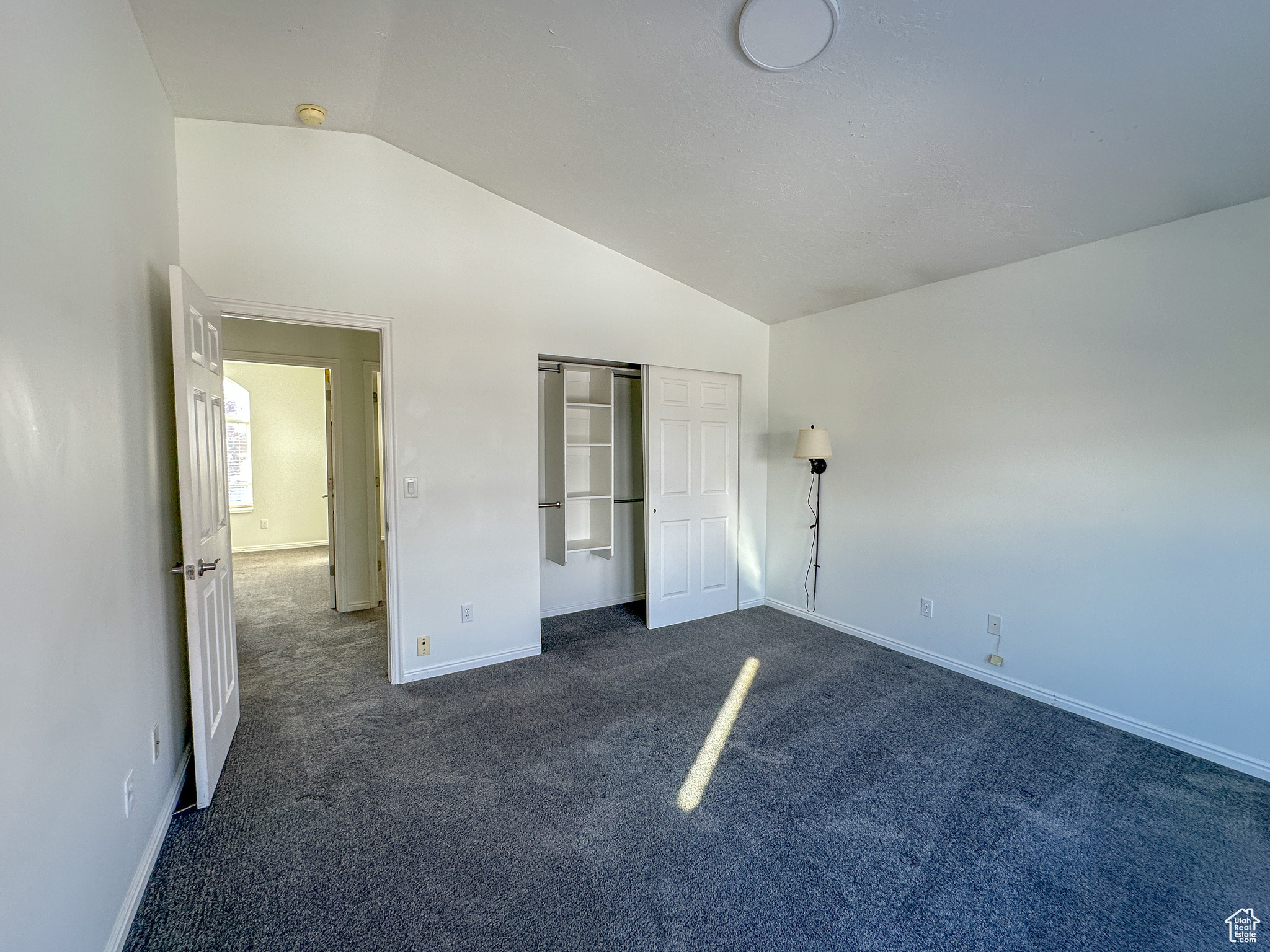 Unfurnished bedroom featuring dark carpet, vaulted ceiling, and a closet