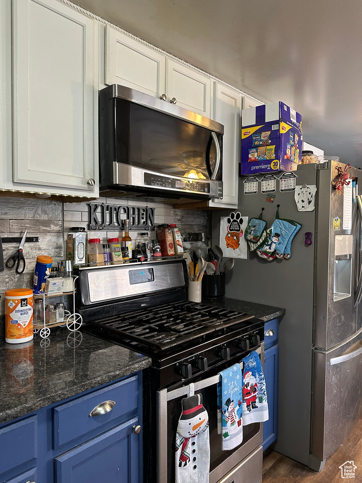 Kitchen featuring dark hardwood / wood-style flooring, dark stone counters, stainless steel appliances, blue cabinetry, and white cabinetry