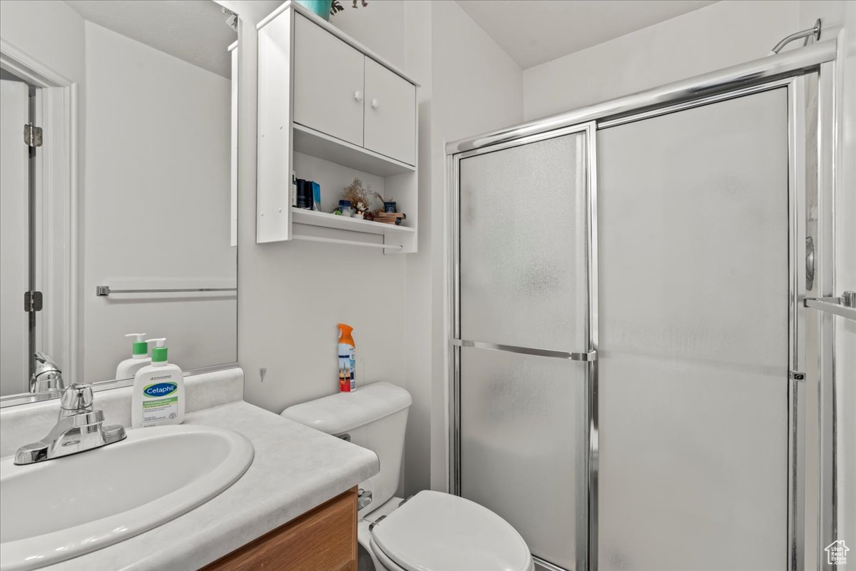 Bathroom with vanity, toilet, and a shower with shower door