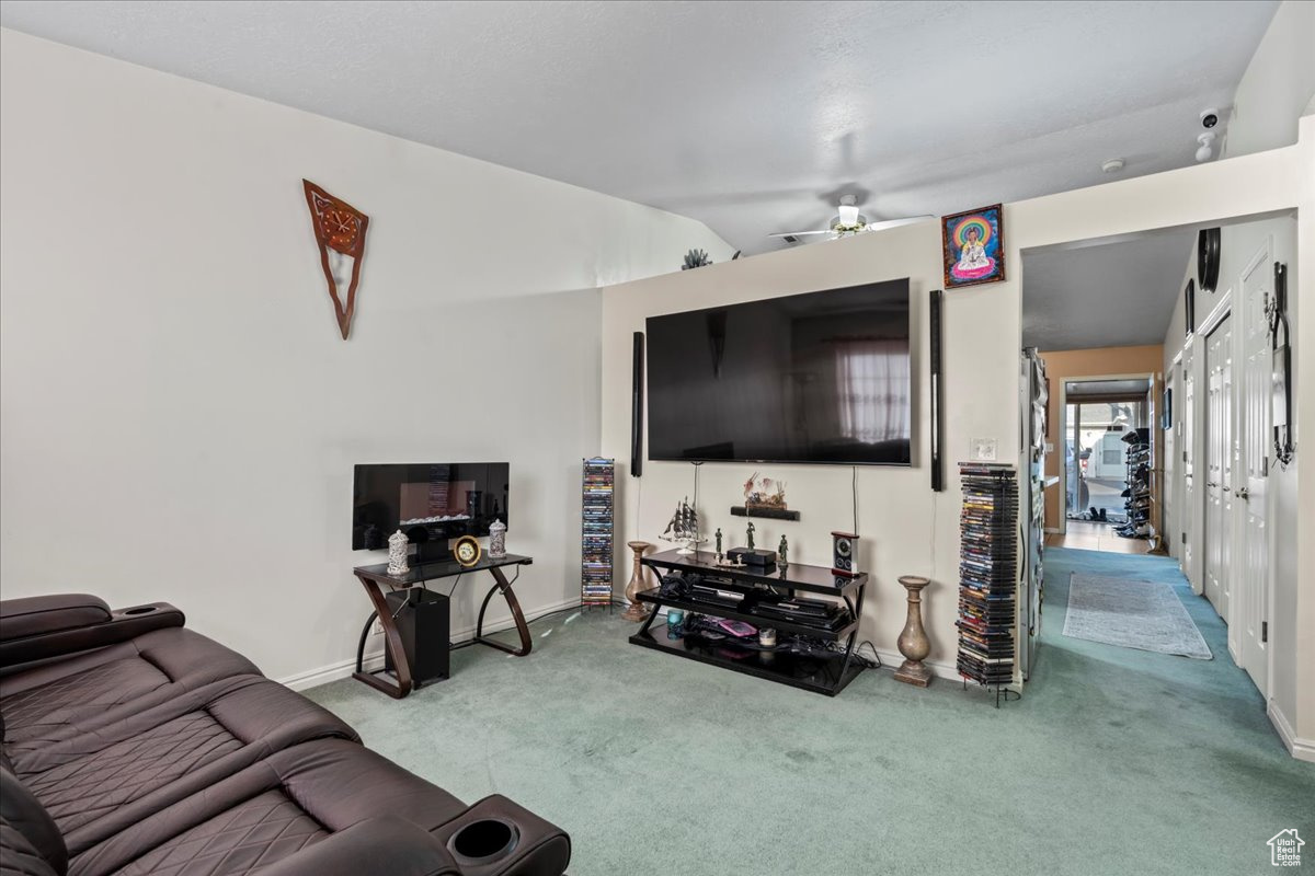 Living room with ceiling fan, carpet floors, and lofted ceiling