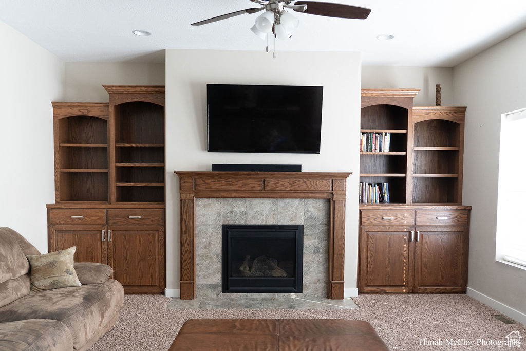 Living room featuring a tile fireplace, light colored carpet, and ceiling fan