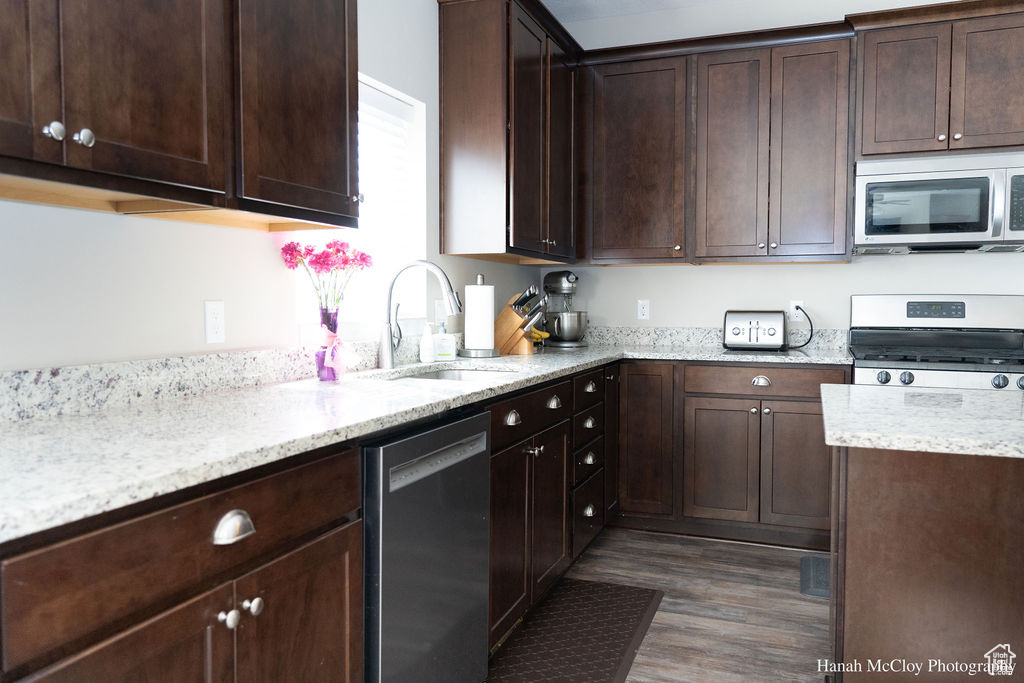 Kitchen with dark hardwood / wood-style floors, sink, dark brown cabinetry, and stainless steel appliances