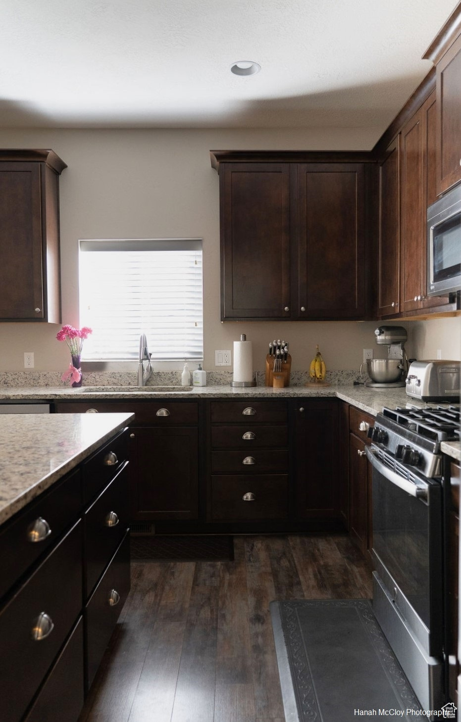 Kitchen with dark brown cabinets, sink, dark wood-type flooring, and appliances with stainless steel finishes