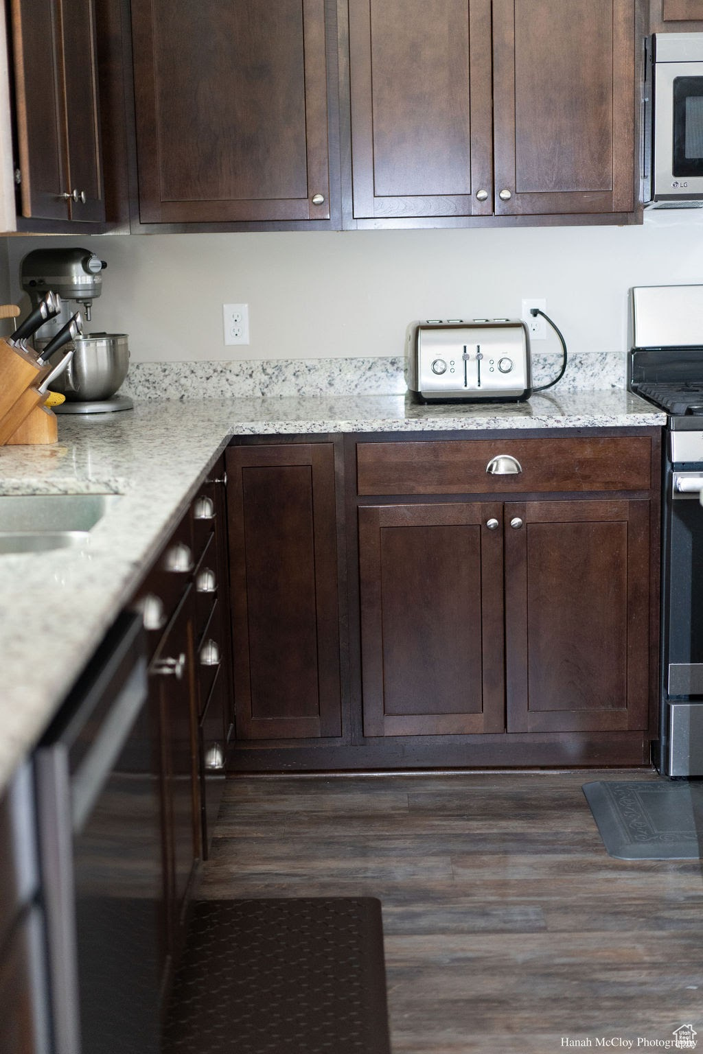 Kitchen with light stone counters, dark brown cabinets, and stainless steel appliances