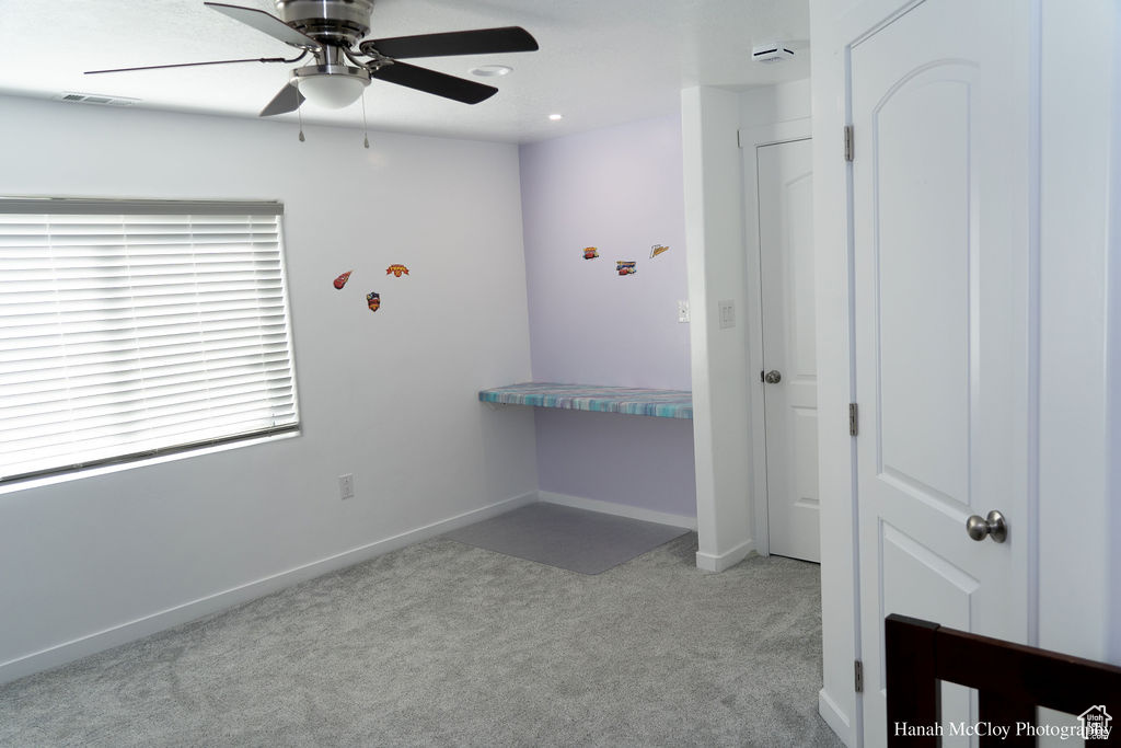 Carpeted bedroom featuring ceiling fan