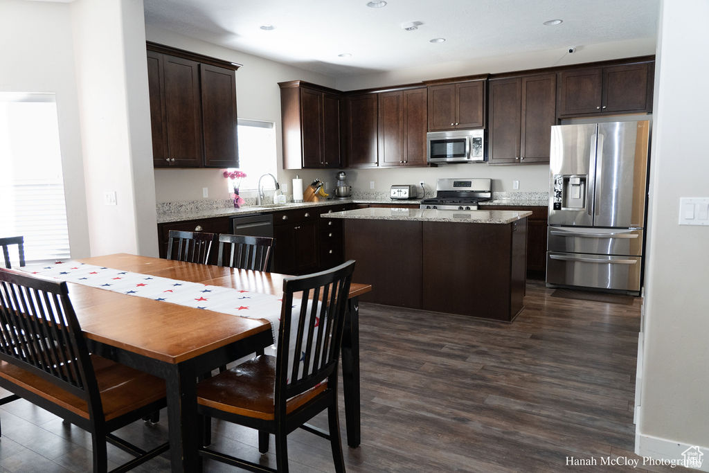 Kitchen with a center island, dark hardwood / wood-style flooring, dark brown cabinetry, and appliances with stainless steel finishes