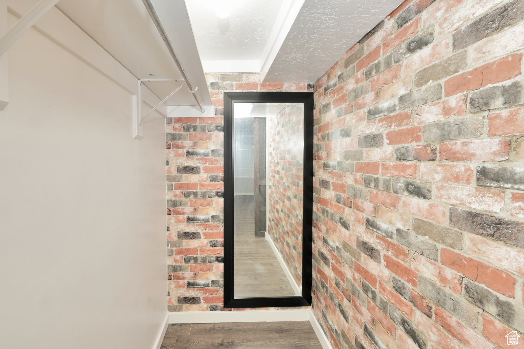 Hallway with dark wood-type flooring and brick wall