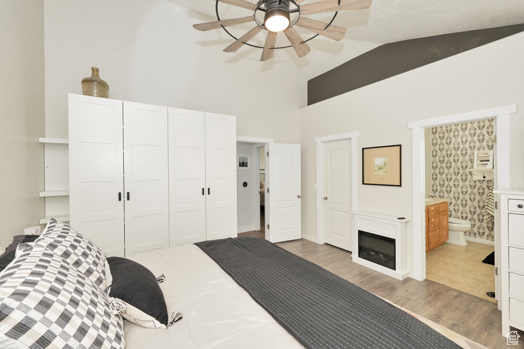 Bedroom with hardwood / wood-style floors, vaulted ceiling, ceiling fan, connected bathroom, and a closet