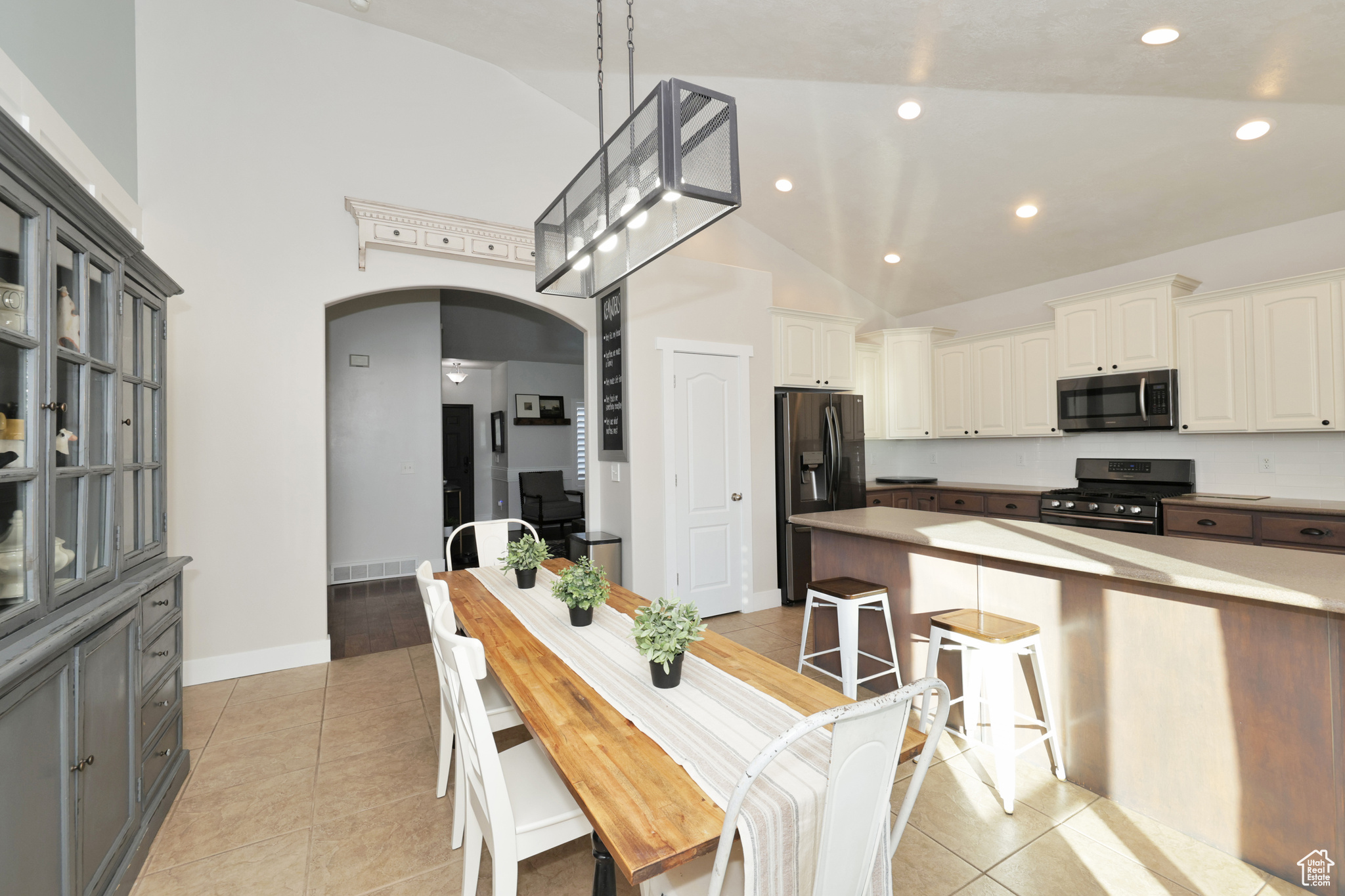 Dining room featuring ceiling fan, light tile patterned floors, and high vaulted ceiling