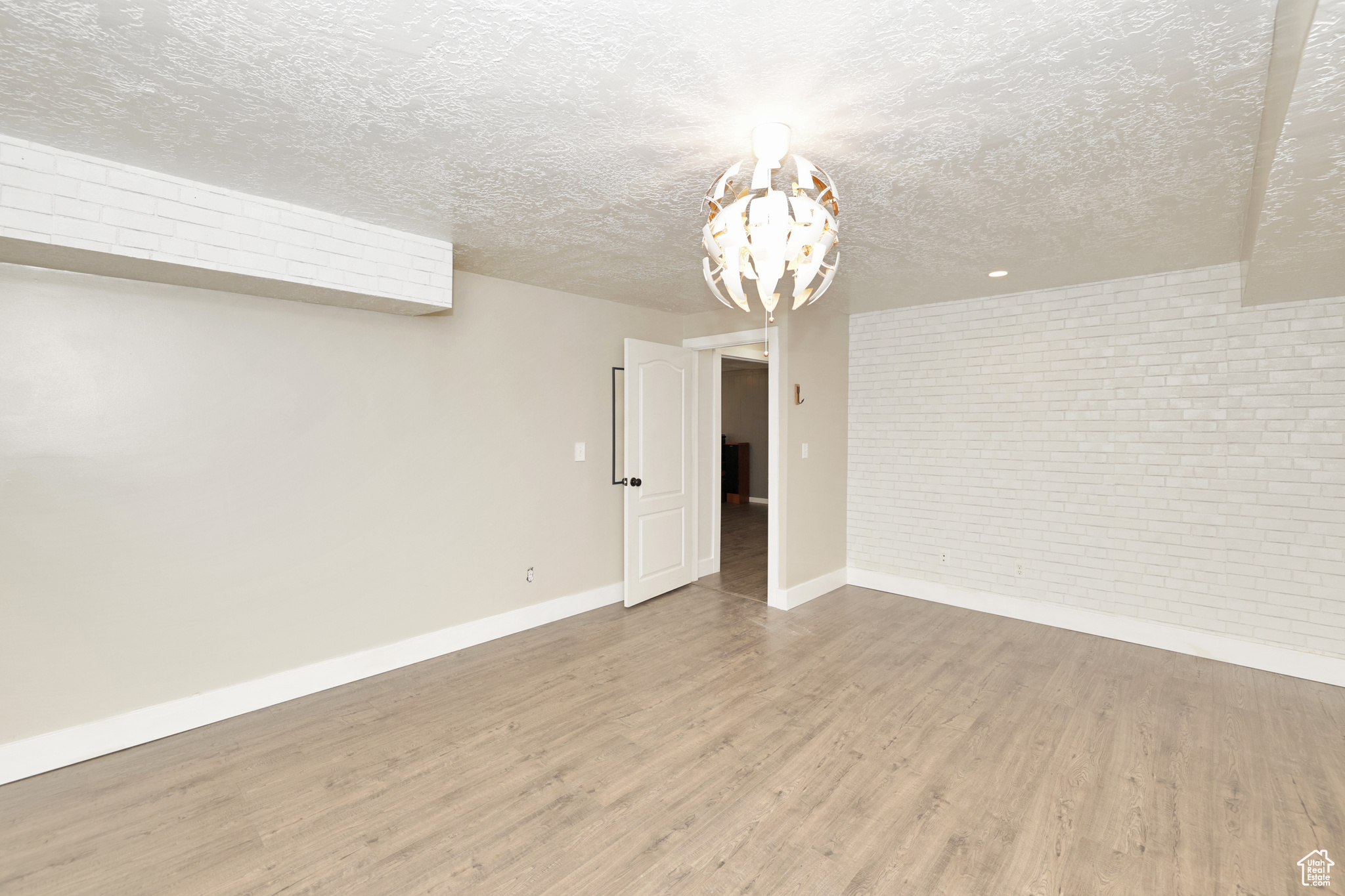 Unfurnished room with hardwood / wood-style floors, brick wall, and a textured ceiling