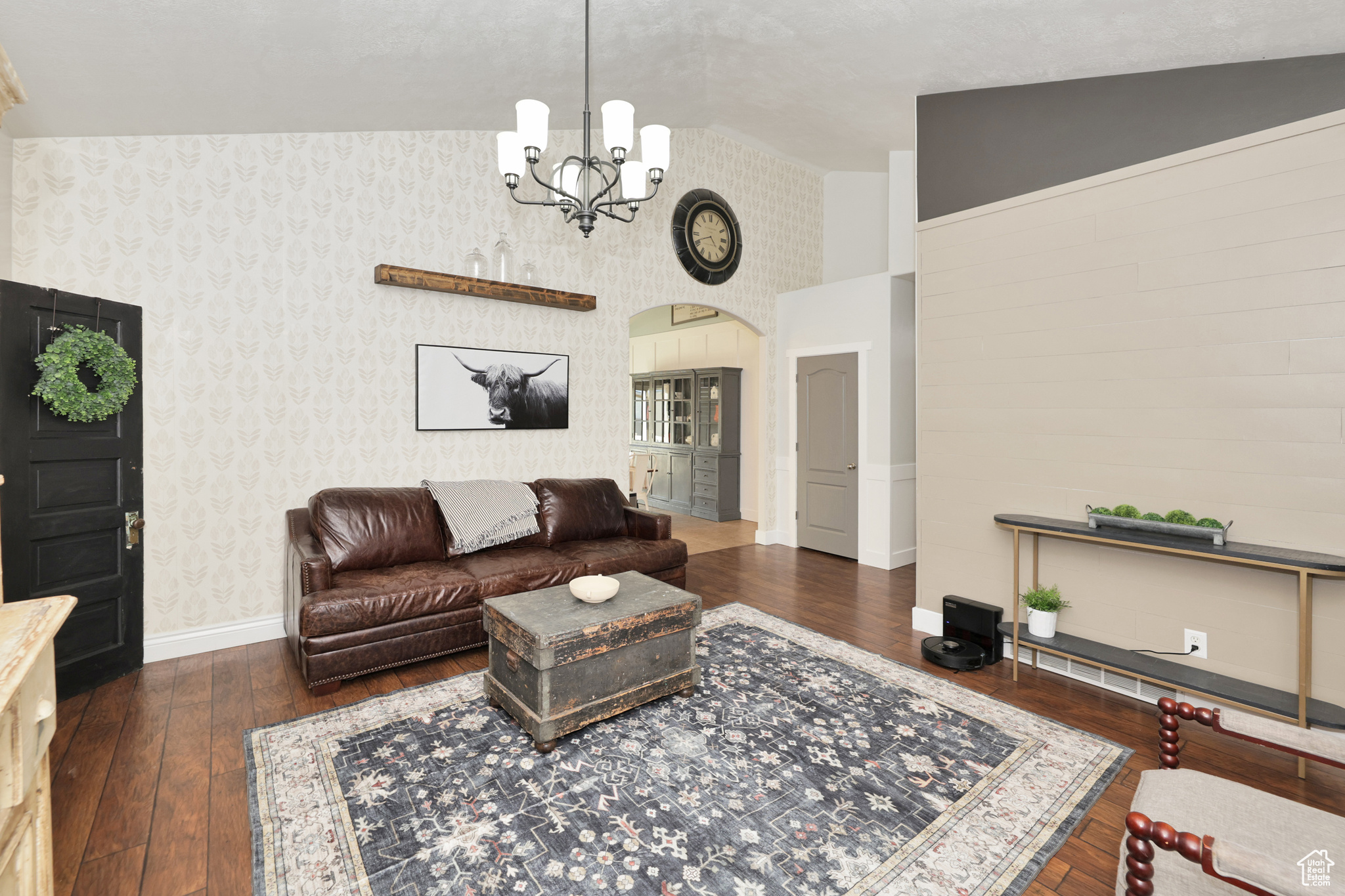 Living room with dark hardwood / wood-style flooring, high vaulted ceiling, and a chandelier