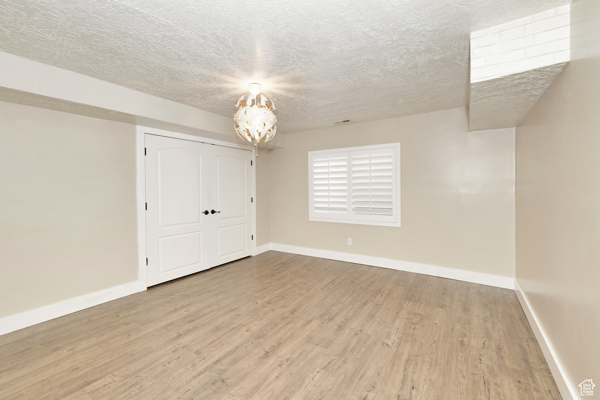 Unfurnished bedroom featuring a closet, a textured ceiling, and light hardwood / wood-style flooring