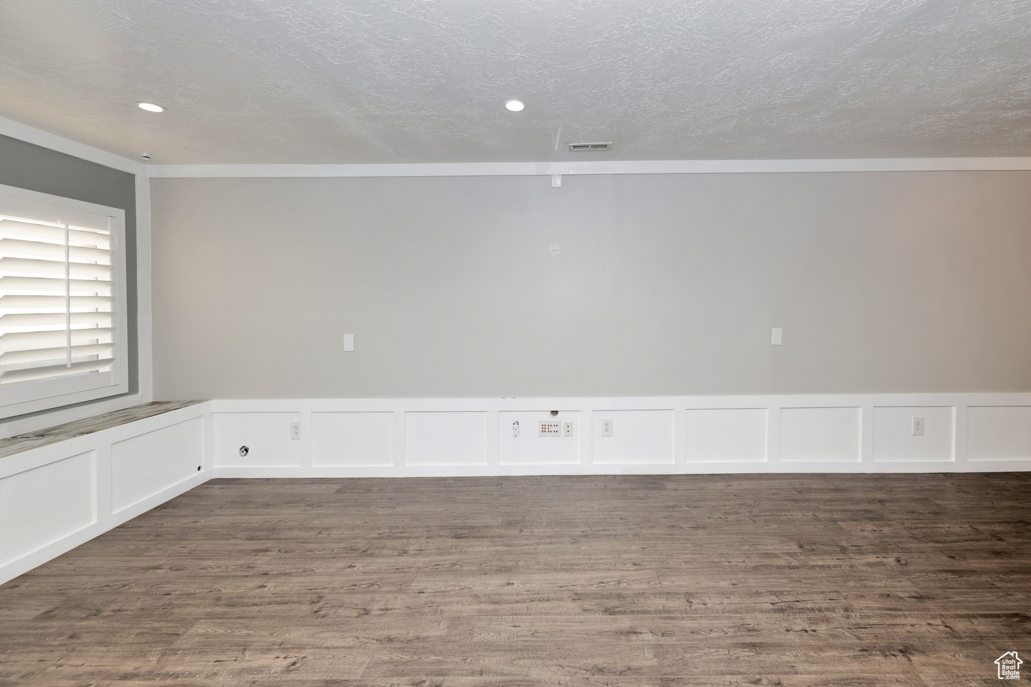 Empty room with crown molding, a textured ceiling, and hardwood / wood-style flooring