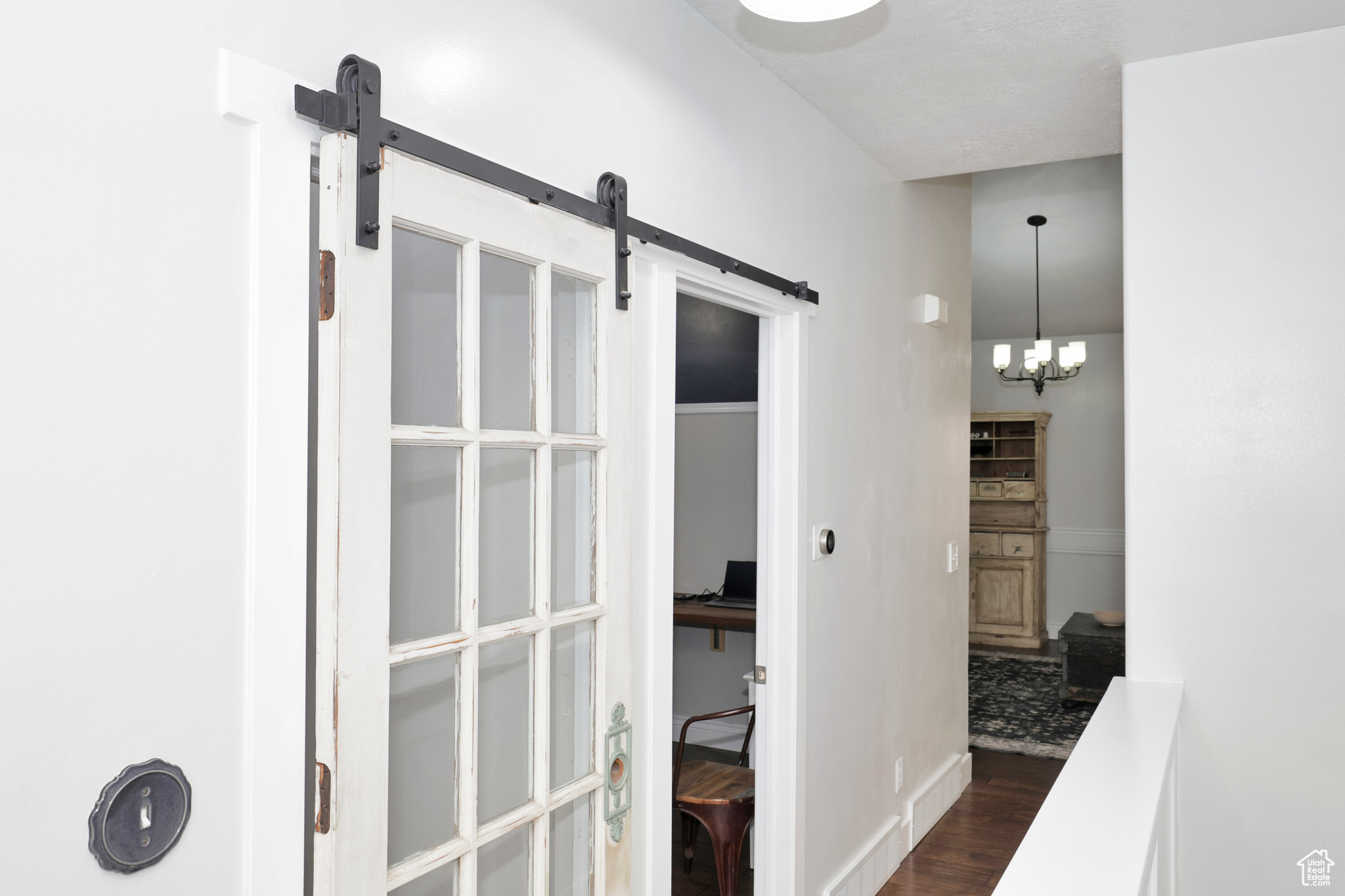 Hallway with a chandelier and dark wood-type flooring