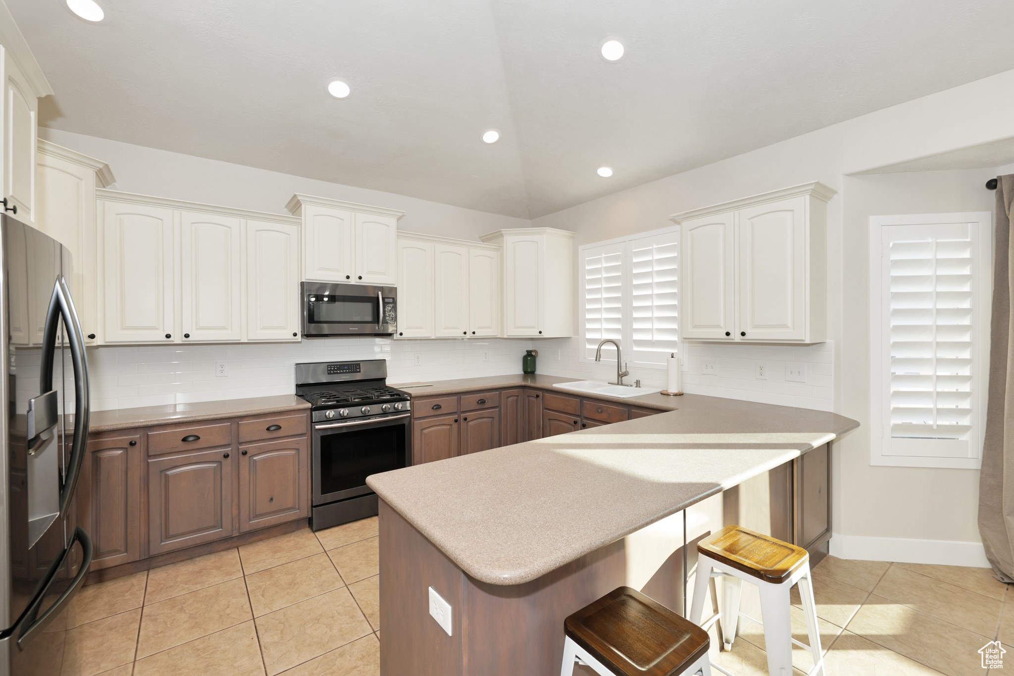 Kitchen featuring a breakfast bar, stainless steel appliances, white cabinetry, and sink