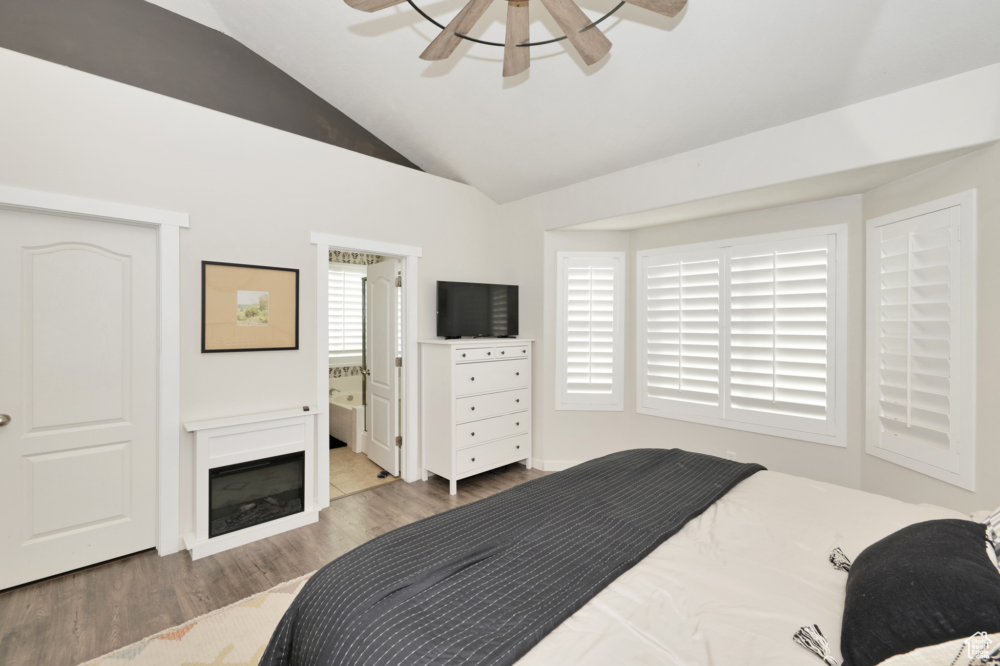 Bedroom featuring hardwood / wood-style flooring, ceiling fan, lofted ceiling, and ensuite bath