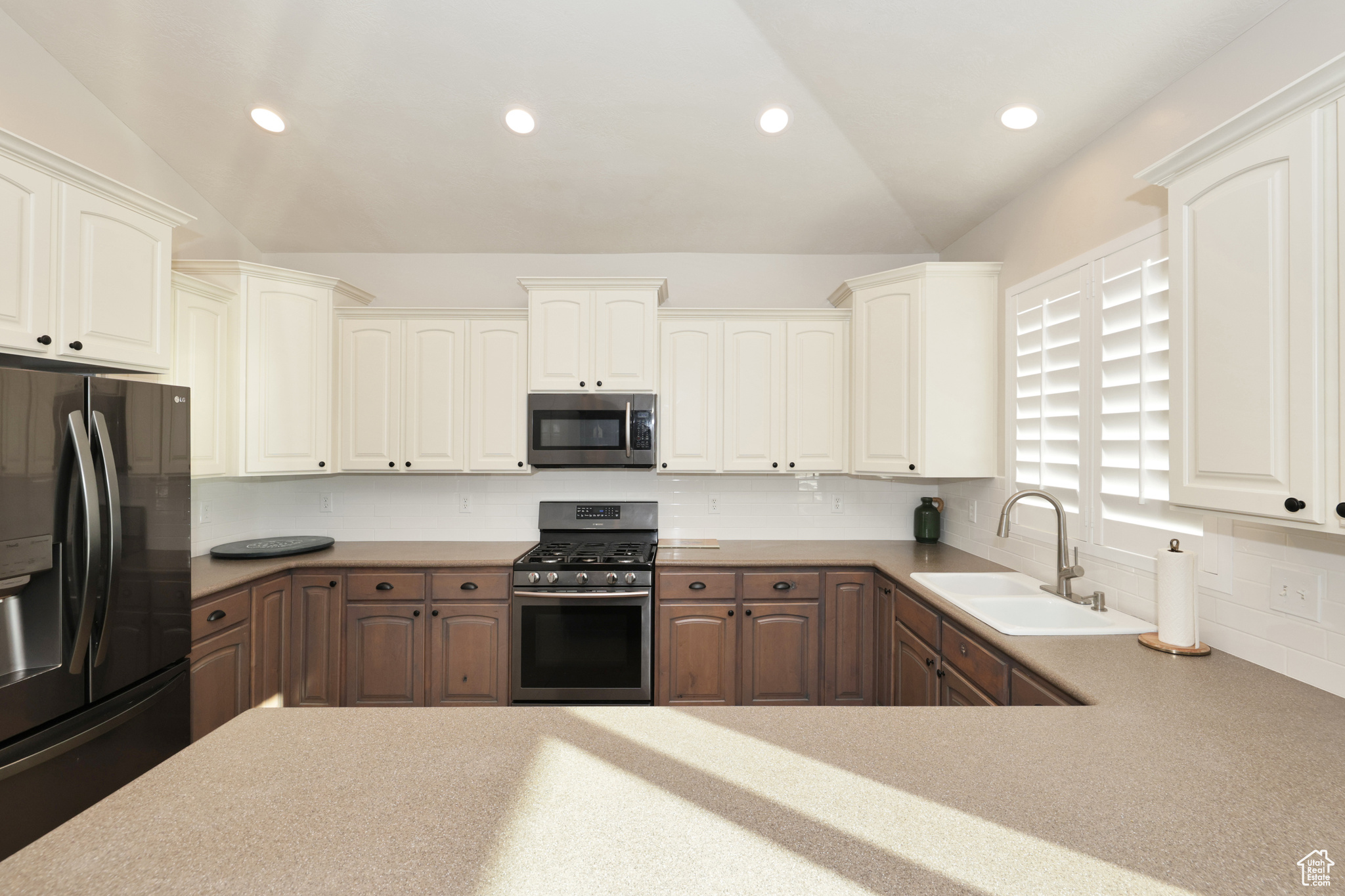 Kitchen with white cabinets, sink, lofted ceiling, and stainless steel appliances