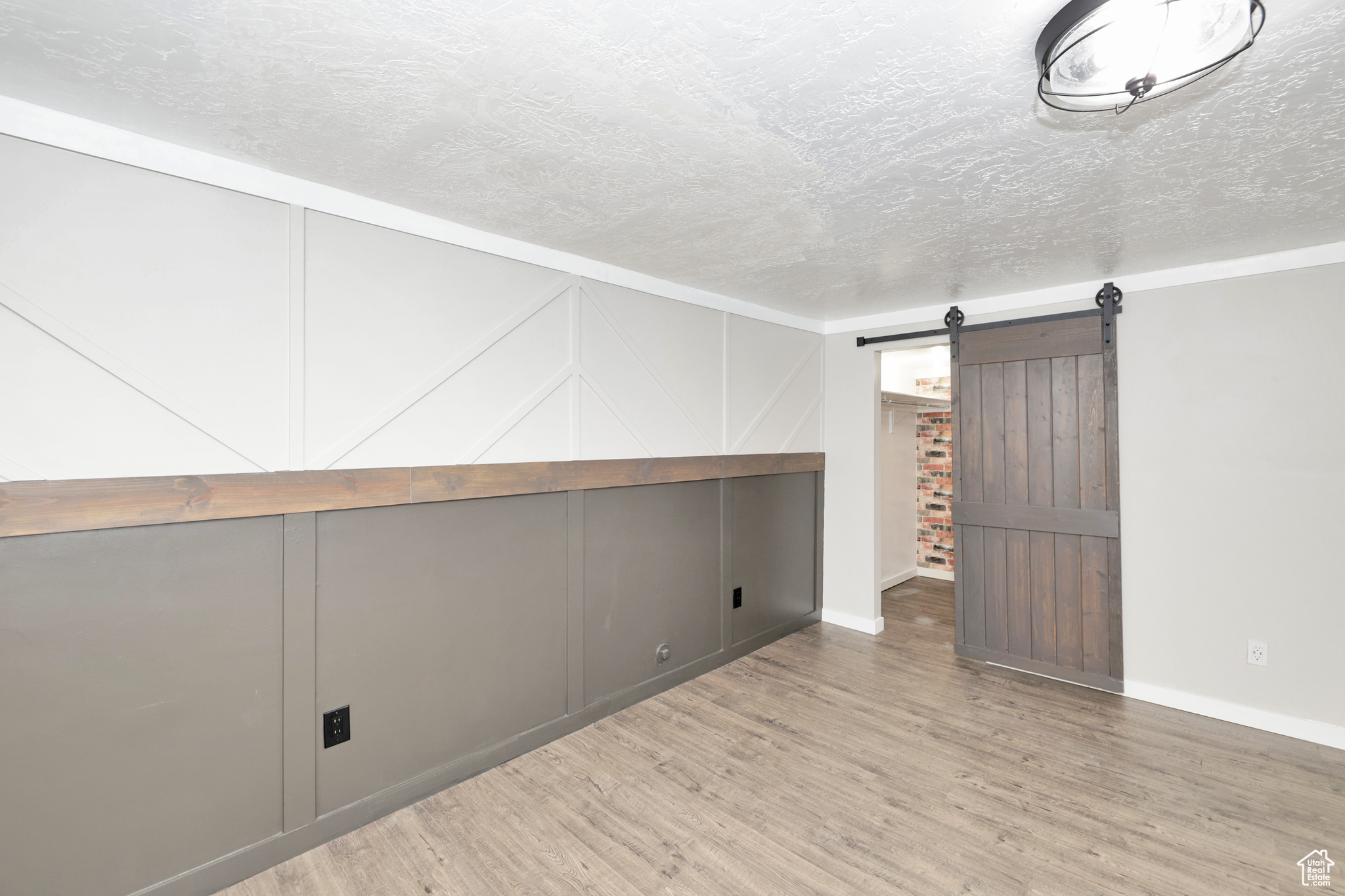 Interior space with a barn door, wood-type flooring, and a textured ceiling