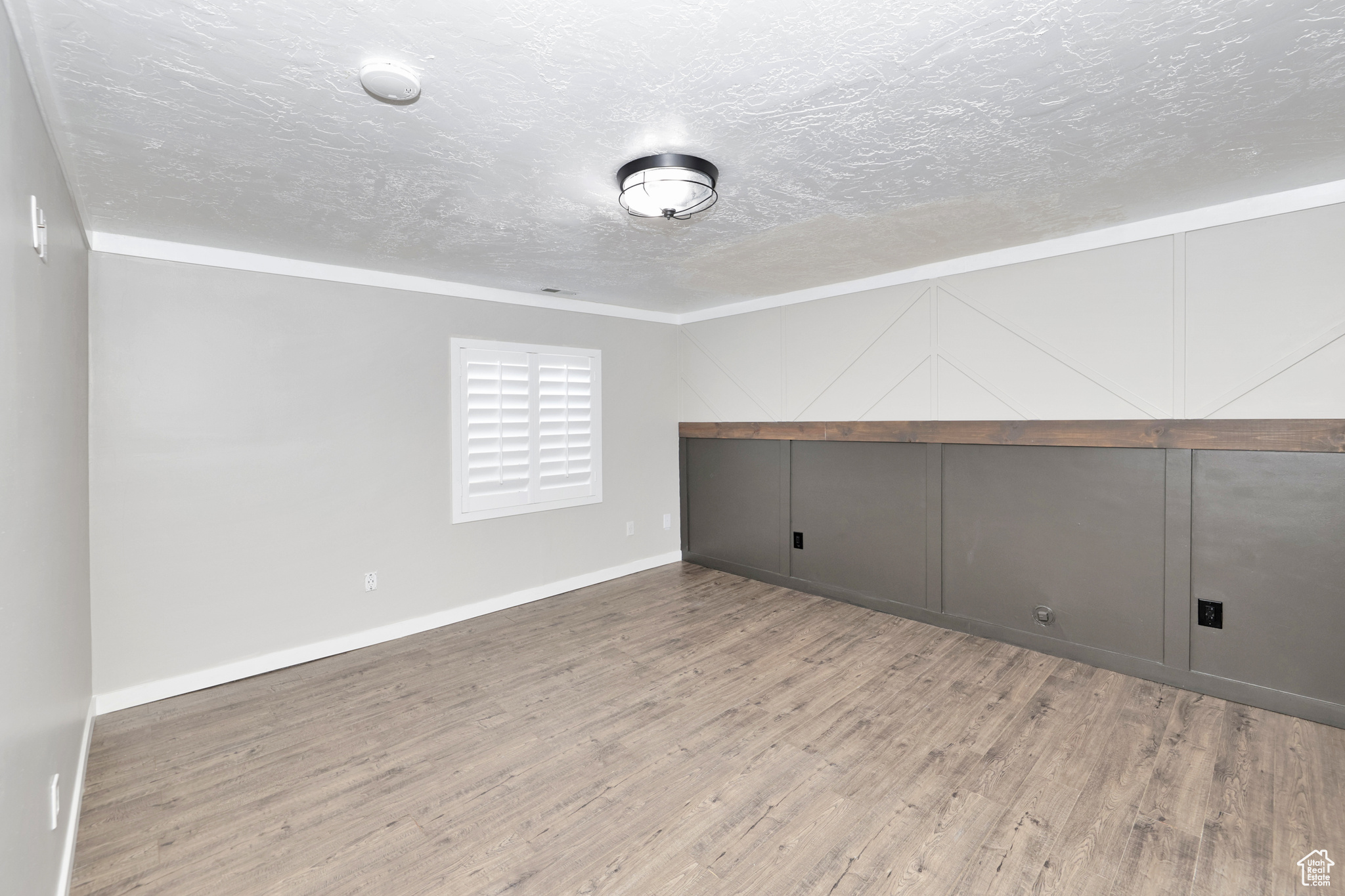 Spare room with crown molding, a textured ceiling, and hardwood / wood-style flooring