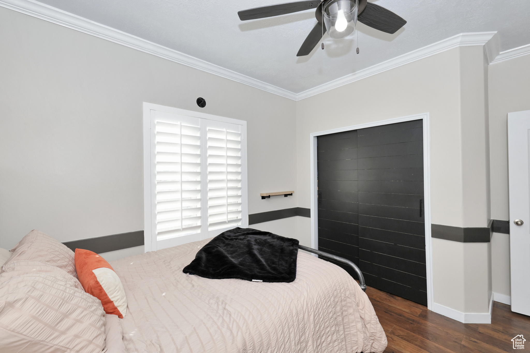 Bedroom with a closet, ceiling fan, crown molding, and dark hardwood / wood-style floors