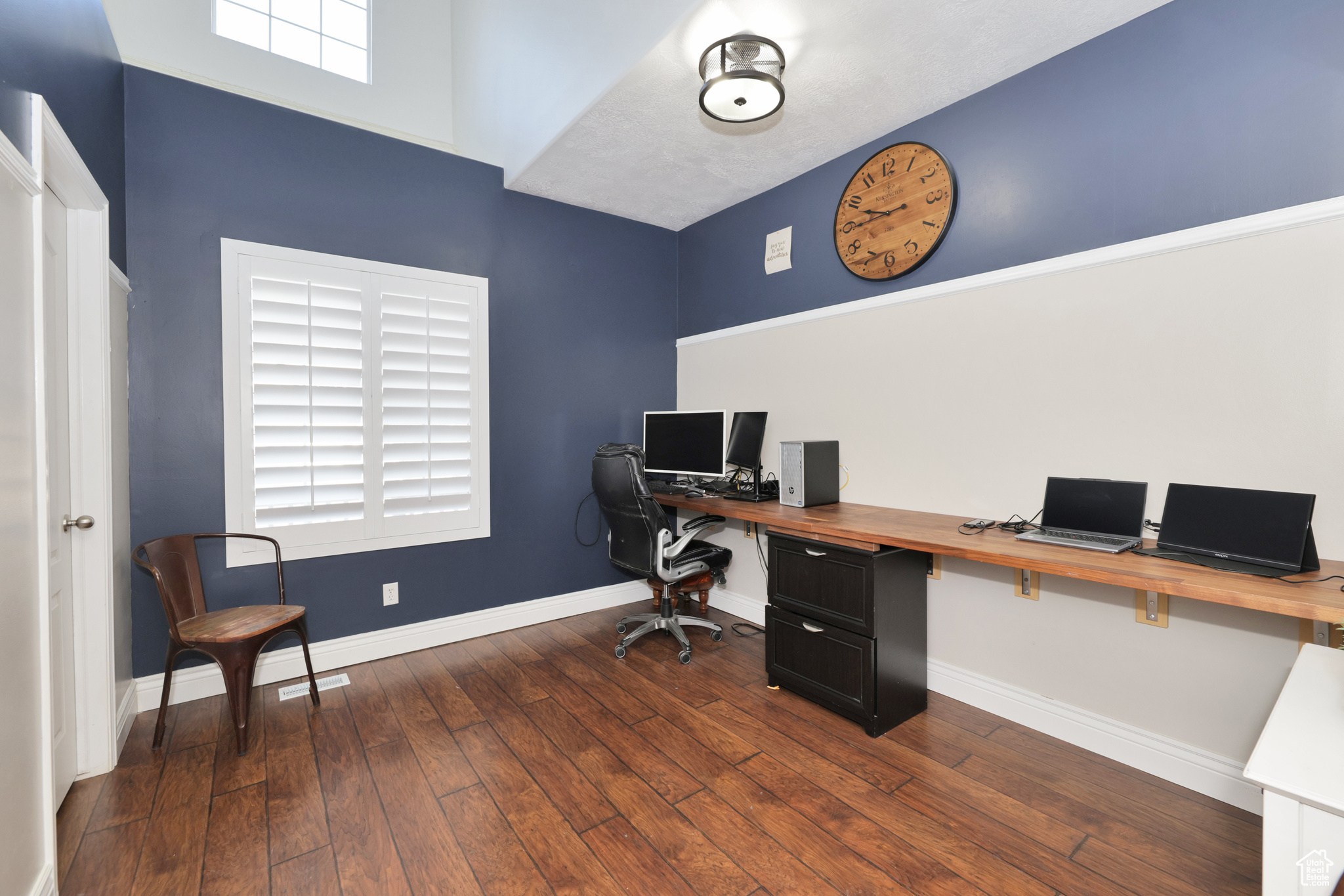 Home office with dark hardwood / wood-style flooring and a healthy amount of sunlight