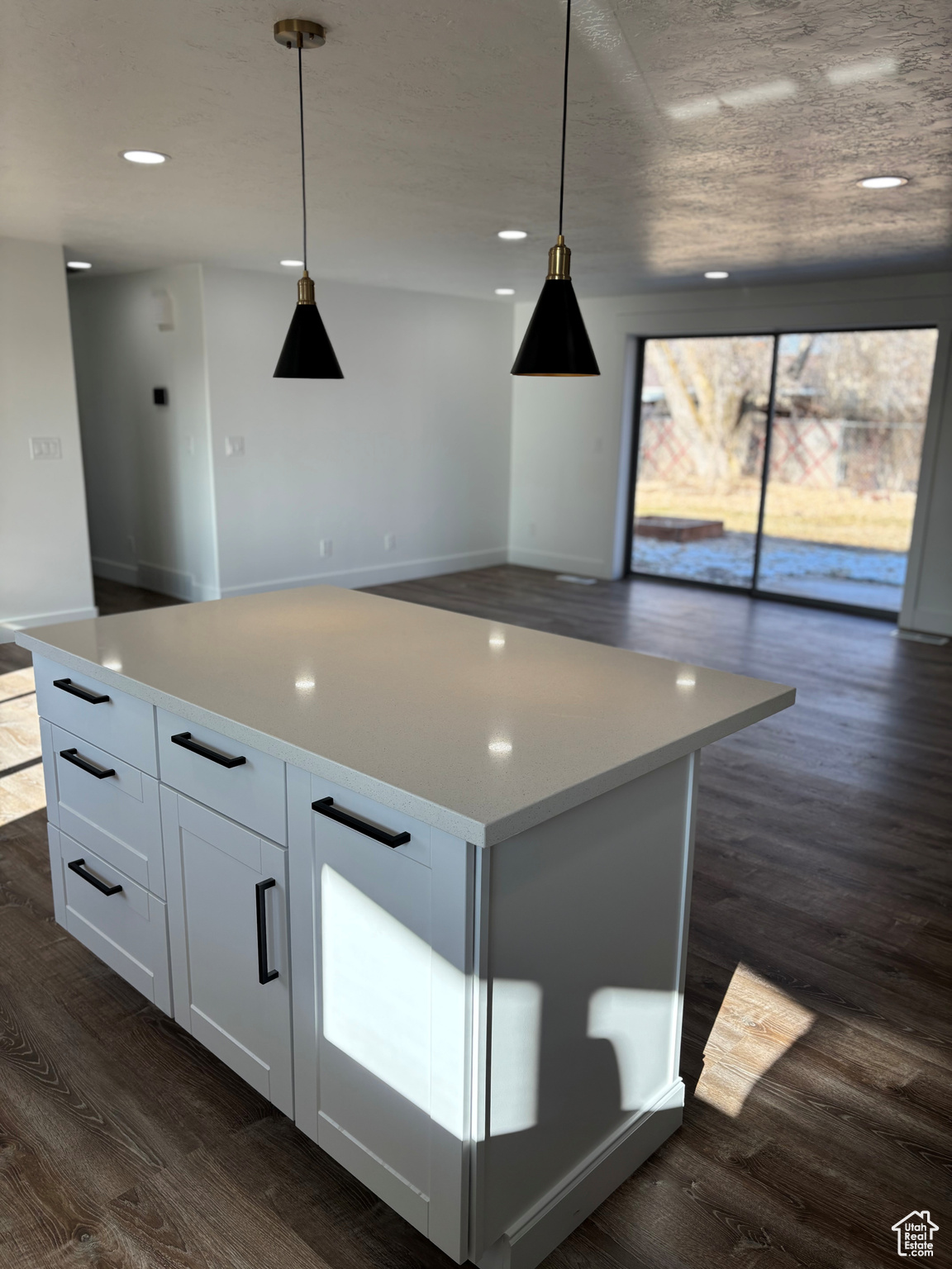 Kitchen featuring a center island, white cabinetry, hanging light fixtures, and dark wood-type flooring