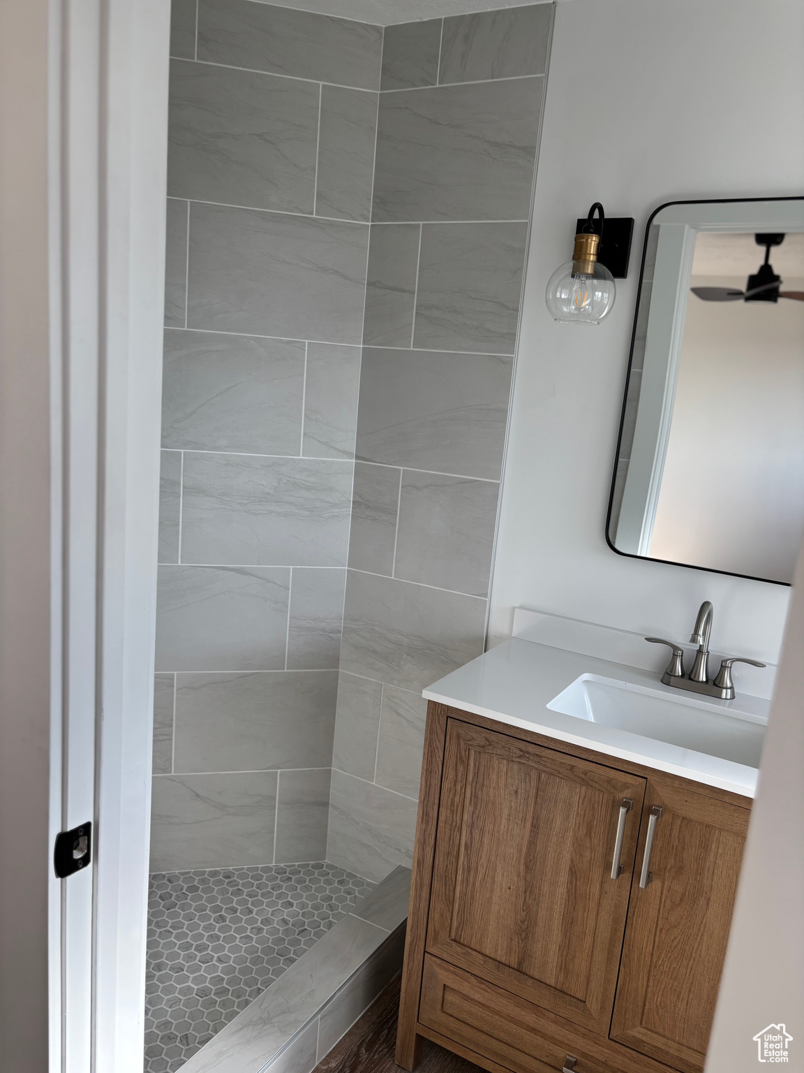 Bathroom with vanity, ceiling fan, and tiled shower