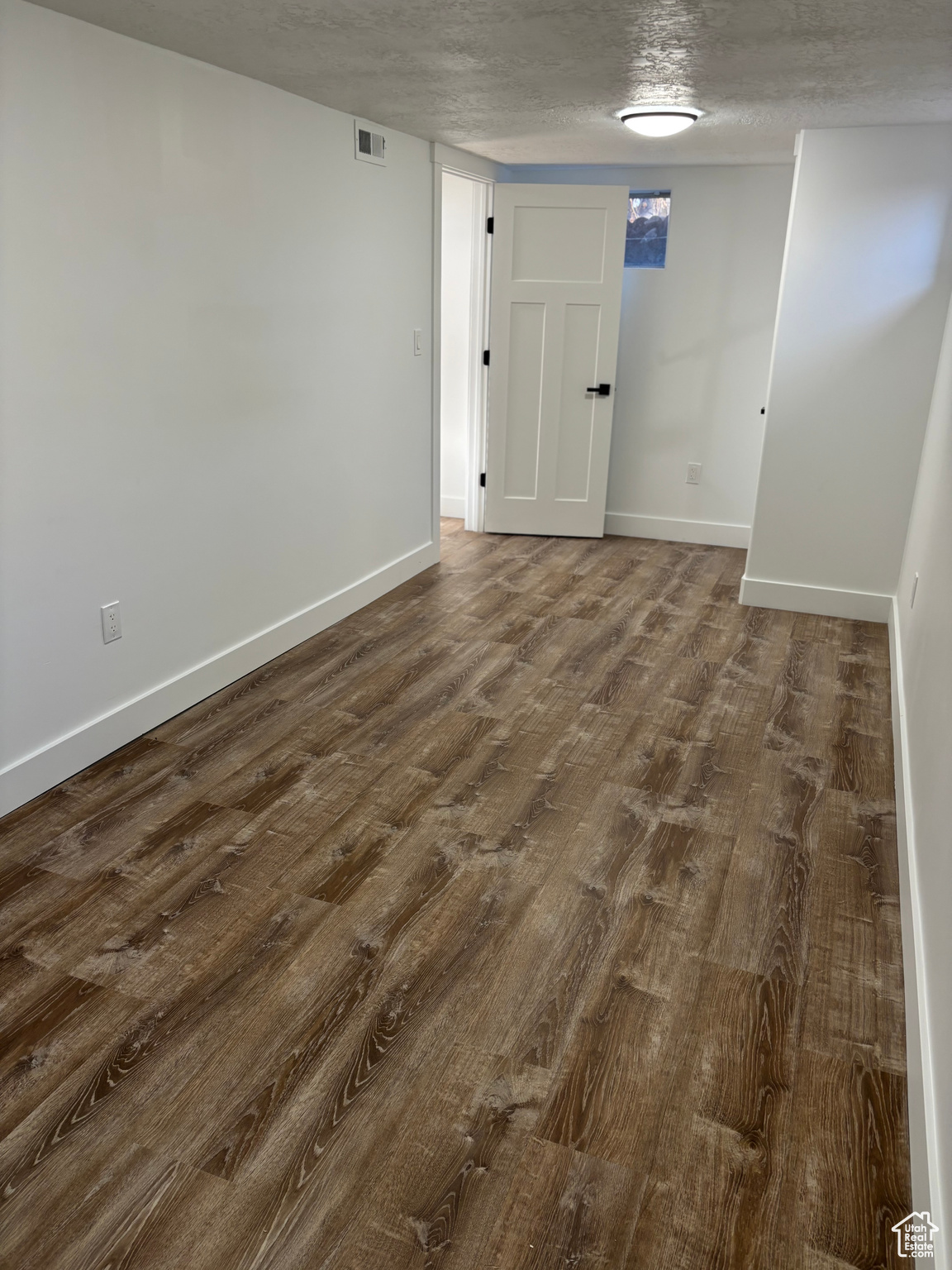 Spare room with dark hardwood / wood-style flooring and a textured ceiling