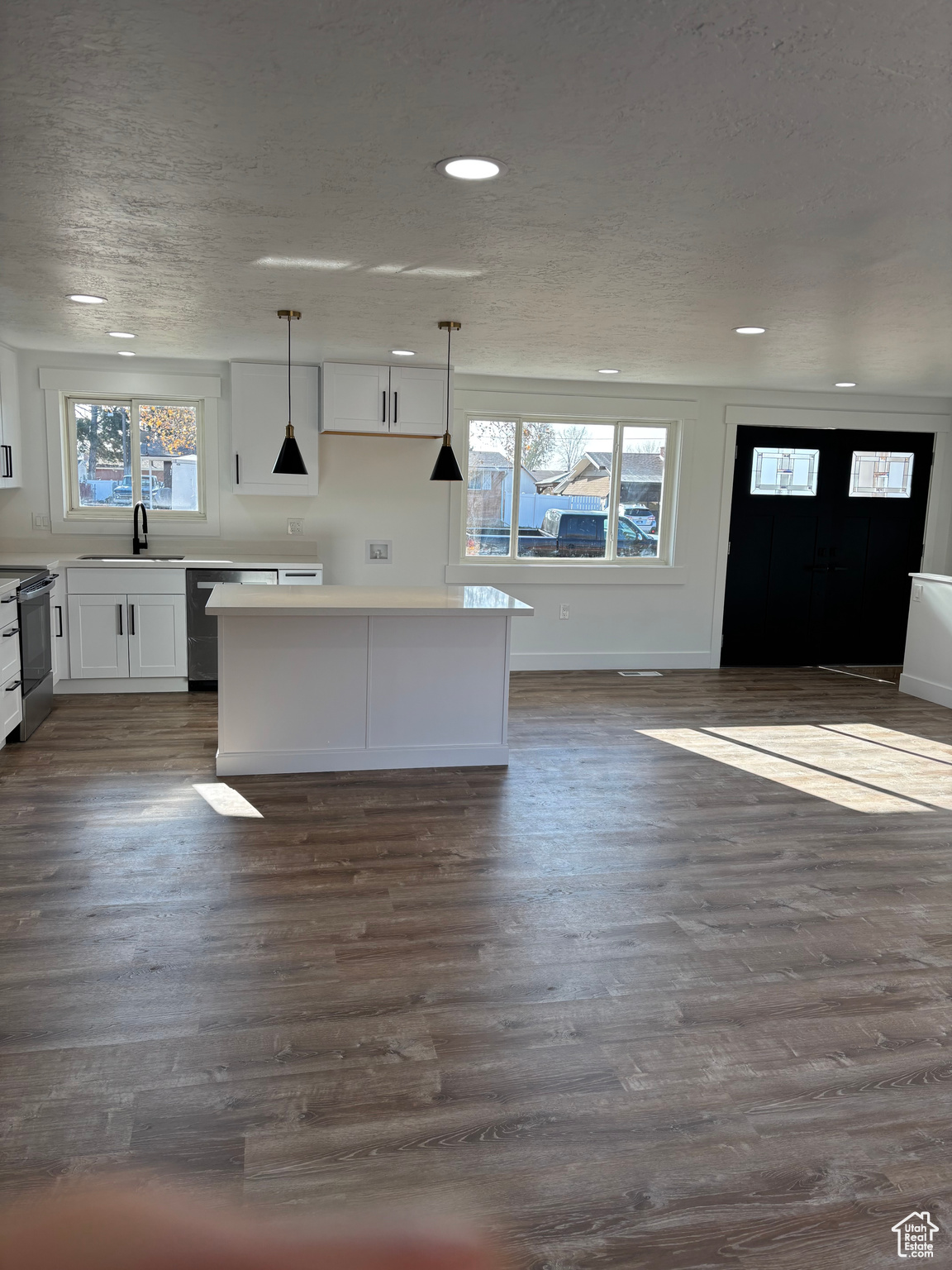 Kitchen with pendant lighting, dark hardwood / wood-style flooring, white cabinets, and a wealth of natural light