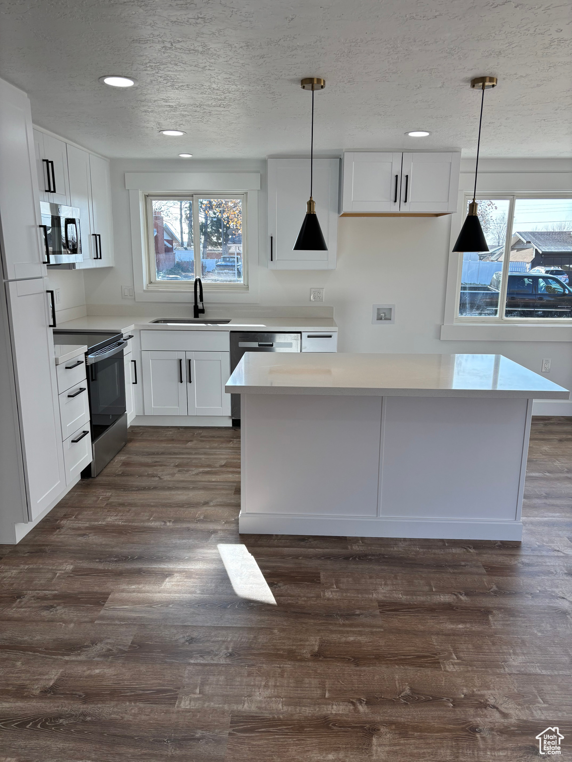 Kitchen featuring sink, white cabinets, and decorative light fixtures