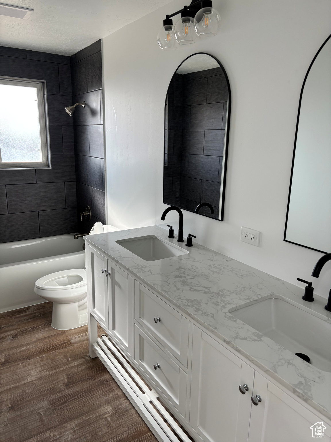 Full bathroom with hardwood / wood-style floors, vanity, toilet, and tiled shower / bath